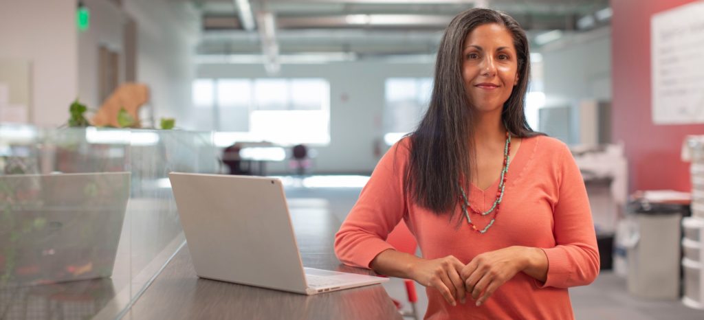 Woman standing near laptop computer in office space