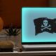 Spooky Graphic For Holiday Website Maintenance. Shows Spooked Jack O Lantern Looking At Computer With Hacked Screen.