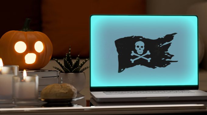Spooky graphic for holiday website maintenance. Shows spooked jack o lantern looking at computer with hacked screen.